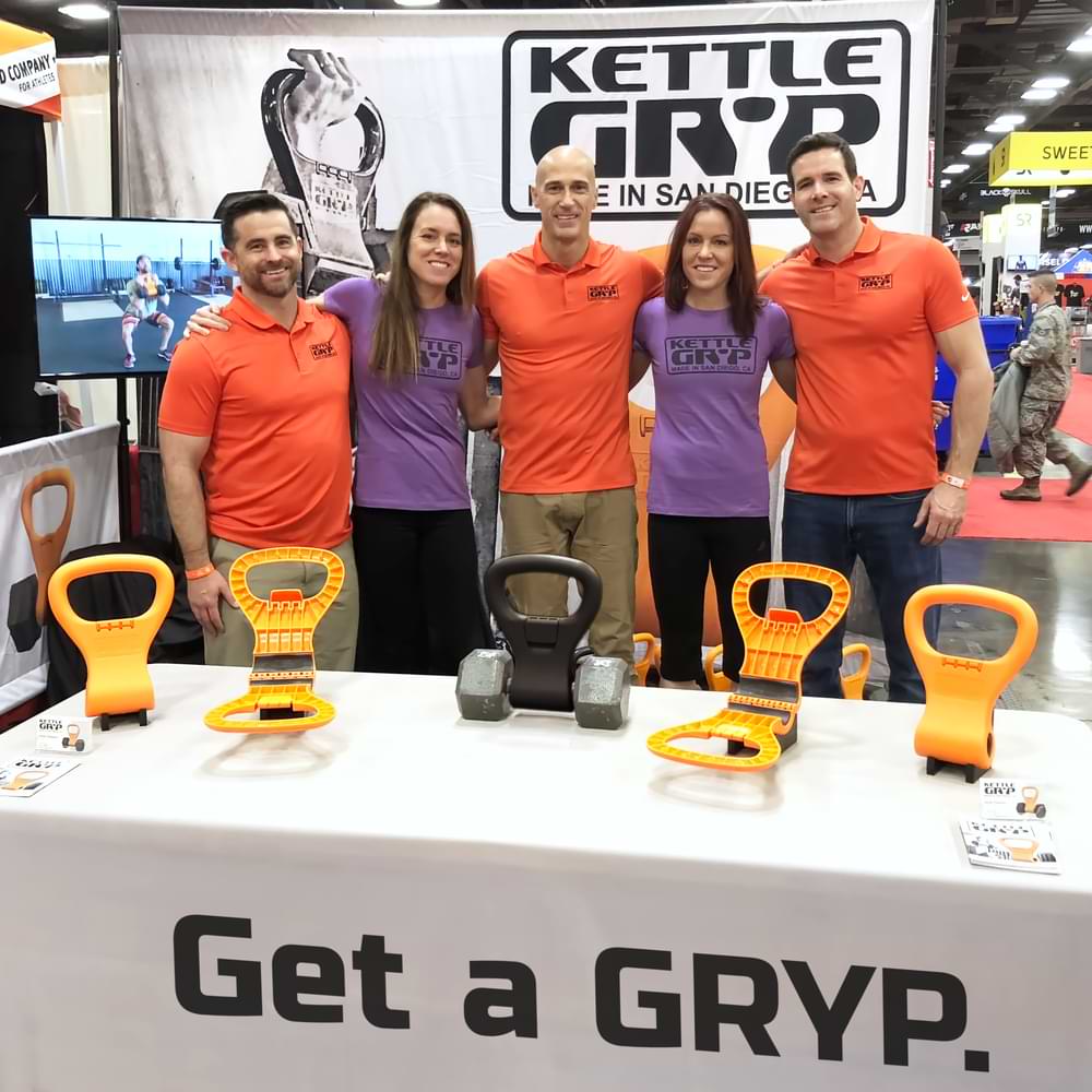 The Kettle Gryp team posing at their fitness expo booth.